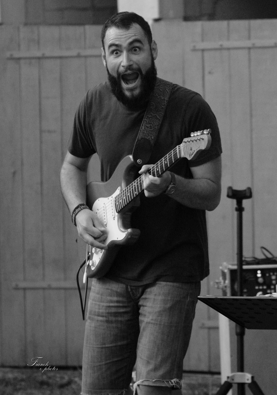 une photo en noir et blanc de Vince qui fait une grimace tout en jouant de la guitare